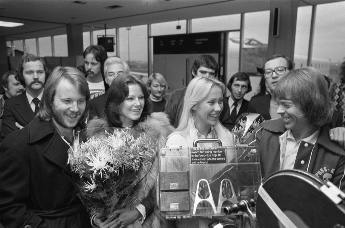 Svartvitt foto av de fyra medlemmarna i ABBA som står bredvid varandra i Nederländerna 1976.